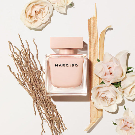 Narciso pink perfume bottle with flowers on a light background